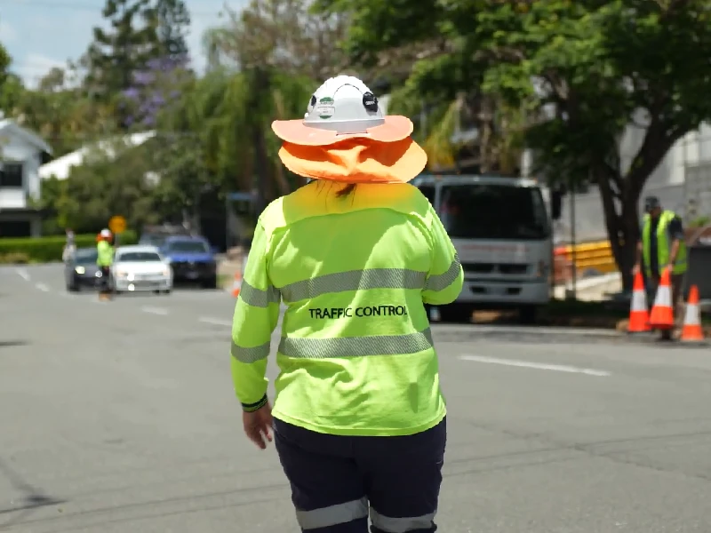 Traffic control worker managing vehicle movement during roadside operations in a residential street
